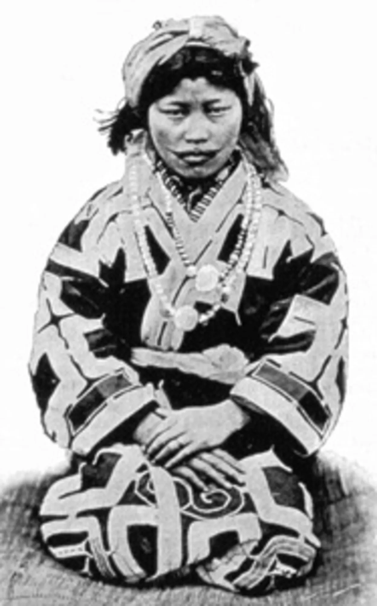 Người phụ nữ Ainu mặc trang phục attush với những họa tiết thêu ma thuật, khoảng năm 1890. Giống như hình xăm, những họa tiết thêu này được cho là có tác dụng ngăn chặn tà ma xâm nhập vào cơ thể.